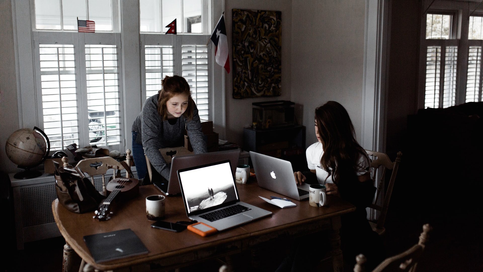 people working on laptops around a dining room table