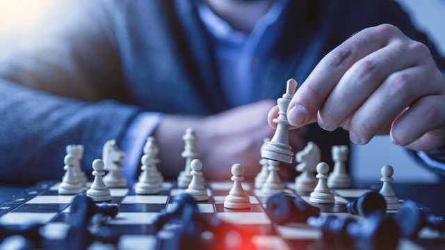 Person moving a chess piece over a board
