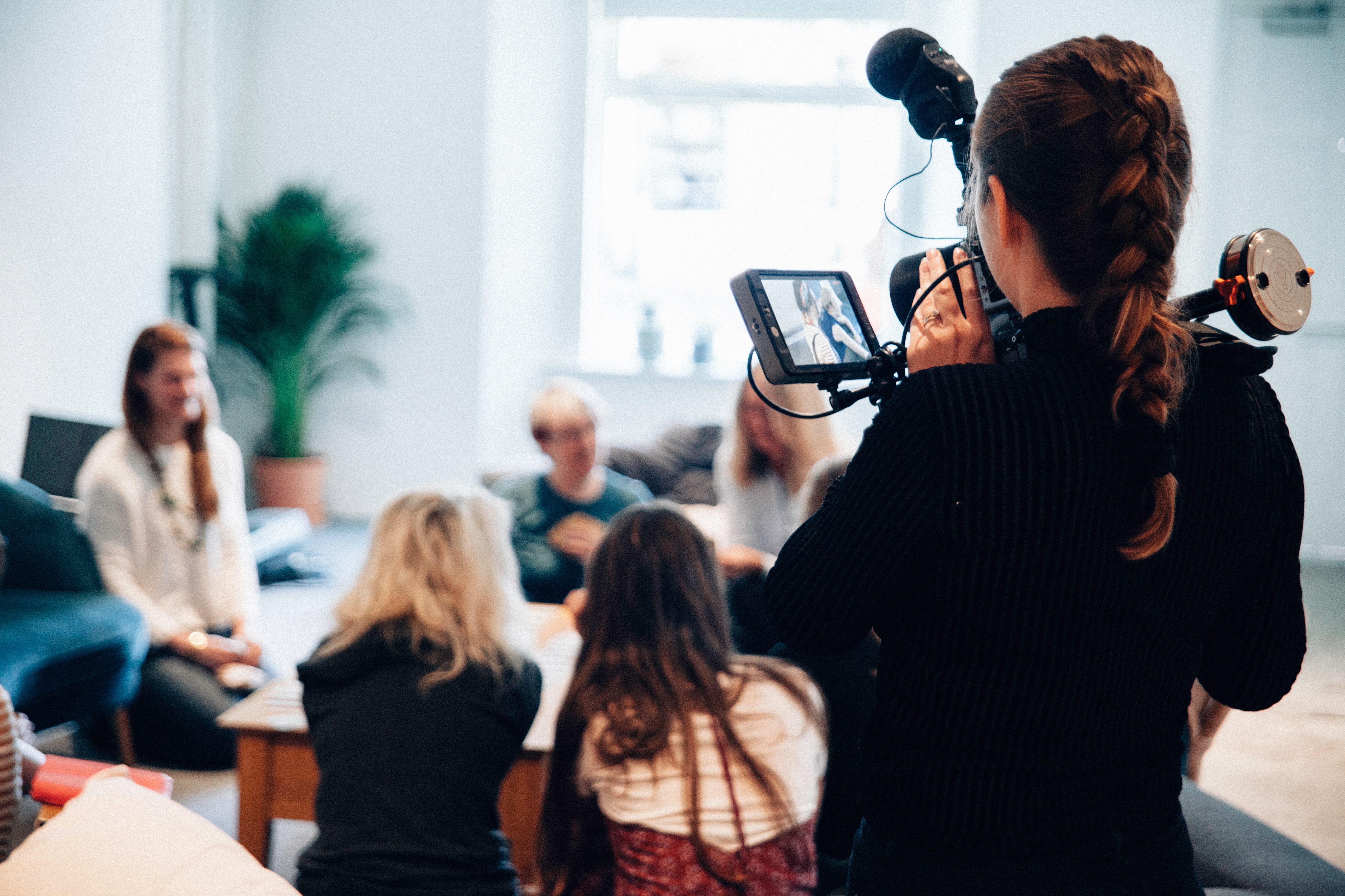 Woman recording a discussion being held by a group of women Woman recording a discussion being held by a group of women